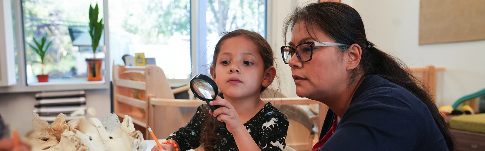 Child with magnifying glass and teacher